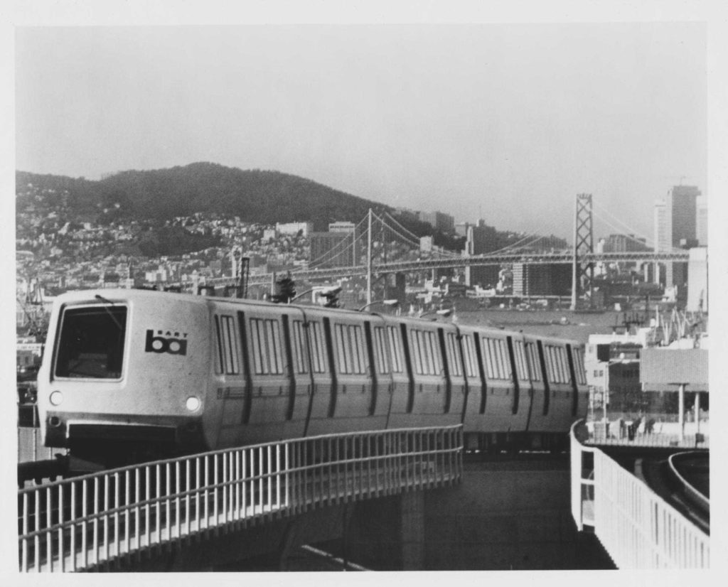 An archival photo of a BART train rolling through in Oakland with San Francisco in the background