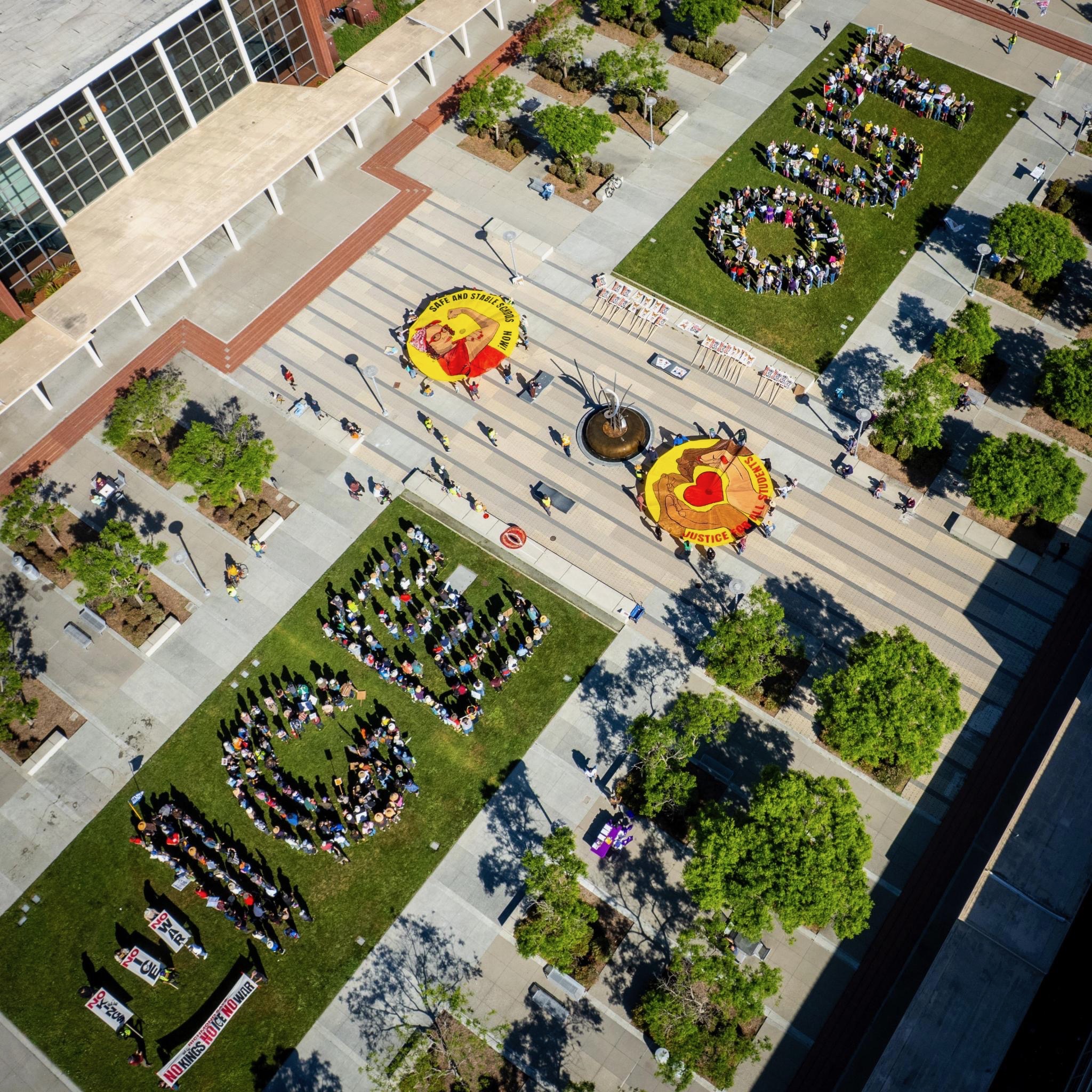 Richmond activists join nationwide 'No Kings' protest against Trump policies Close to 500 residents gathered at the Richmond Civic Center on Saturday to join the massive nationwide mobilization titled the "No Kings" rally. The local event, which featured a human banner, a downtown march, and a resource fair, was part of a coordinated effort across more than 3,100 locations nationally to protest the Trump administration’s military actions and domestic policies. The Richmond action was organized by a broad coalition of local groups, including Richmond Indivisible, the United Teachers of Richmond (UTR), the Richmond Progressive Alliance, and the Democratic Socialists of America. Other partners included the Contra Costa Labor Council and the Asian Pacific Environmental Network (APEN). "I think it was a huge success," said Kathleen Marte, an organizer with Richmond Indivisible. "We were expecting maybe 300 people, and the fact that it had three phases—a human banner, a march, and a rally—and it all went so smoothly according to plan was wonderful." The day began at 10 a.m. with a land acknowledgement by Allison of the organization Idle No More, followed by an address from Richmond Mayor Eduardo Martinez. Participants then formed a "human banner" on the Civic Center lawn, with over 450 people positioned to spell out the word "OUT" and "ICE" to signal opposition to recent immigration enforcement and military escalations. Following the visual demonstration, the crowd marched up Barrett Avenue to 32nd Street before turning onto Macdonald Avenue. The procession passed back by the Civic Center and concluded at the parking lot located at 25th Street and Barrett Avenue, across from the Richmond Art Center. The concluding rally featured a diverse lineup of speakers, including City Councilmembers Claudia Jimenez and Doria Robinson, alongside union members and students. The Ballet Folklorico group Lolita and a local DJ performed. The "No Kings" movement, spearheaded nationally by the progressive organization Our Revolution, aims to highlight growing dissatisfaction with the Trump Administration's military spending and what organizers describe as authoritarian overreach.  "At a time when families are struggling to afford basic necessities, this administration is choosing to invest in war and reward billionaire donors," stated Joseph Geevarghese, executive director of Our Revolution. In Richmond, organizers emphasized the peaceful and non-partisan nature of the gathering. Marte noted that the crowd represented a wide cross-section of the community in terms of age and ethnicity, all "uniting against fascism and cruelty." Local activists are already looking toward future mobilizations. The coalition plans to meet this week to coordinate a "May Day Strong" event on May 1, which will carry the theme "Workers Over Billionaires" to continue advocating for economic justice and community resources.